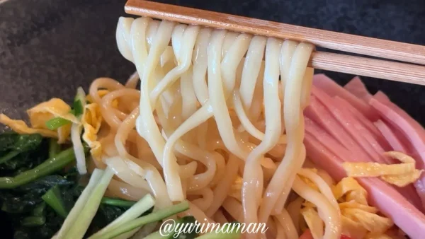 GOLDEN GORILLAの冷やし中華を箸で持ち上げた中太平麺のアップ
