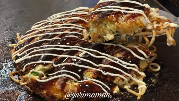 道とん堀新居浜店のお好み焼きを箸で持ち上げたシーン。とろっとした食感が伝わる断面。