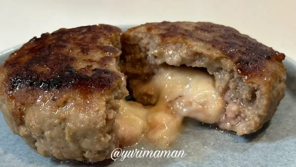 チーズ入り生ハンバーグを割った写真。中からとろけたチーズがあふれる様子。