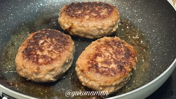 生ハンバーグをフライパンで焼いている様子の写真。焼き目がおいしそうに仕上がった状態。