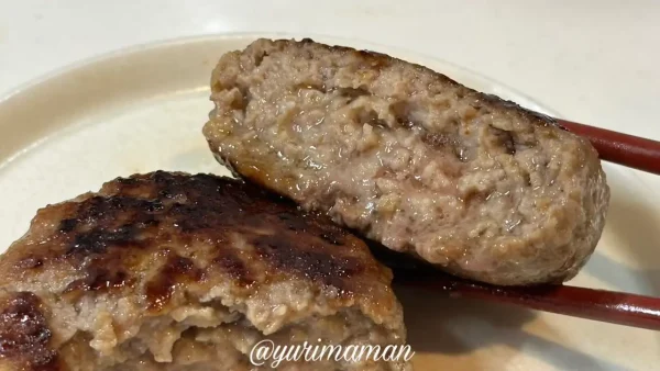 焼いた生ハンバーグを箸で割った瞬間、肉汁があふれている様子の写真。ジューシーな断面。