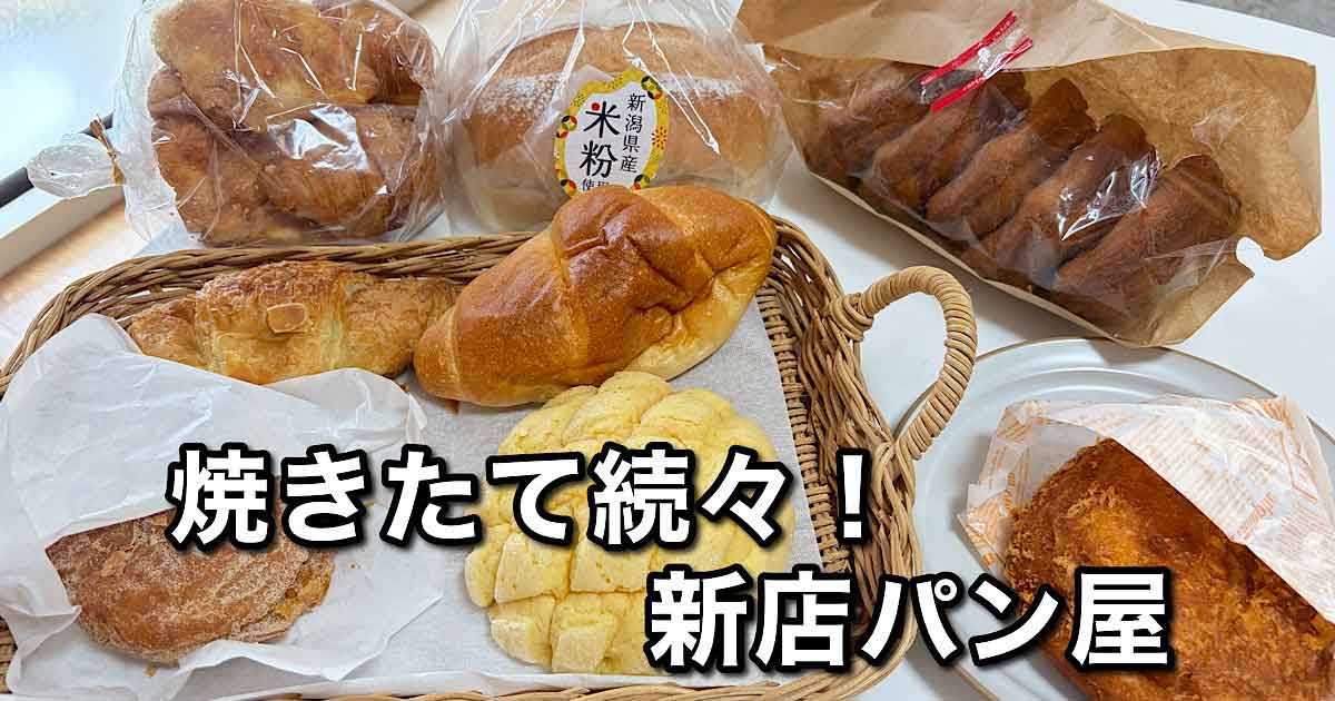 Assorted freshly baked breads in baskets and bags on a table, with bold Japanese text advertising a new bakery.