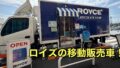 Blue Royce Chocolate Shop mobile truck with striped awning and an OPEN sign outside a crosswalk area.