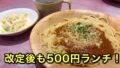 Spaghetti with meat sauce and grated cheese on a wooden plate, with a side salad and a mug nearby; bold Japanese text promoting a 500 yen lunch.
