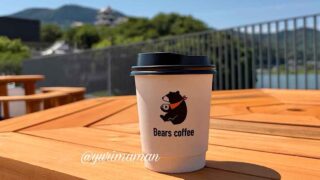 Bears Coffeeの大洲ブレンドと大洲城下町散策の様子 - ゆりママんブログ Disposable coffee cup with Bears coffee logo on a wooden outdoor table, bright sunny day with railing and hills in the background.