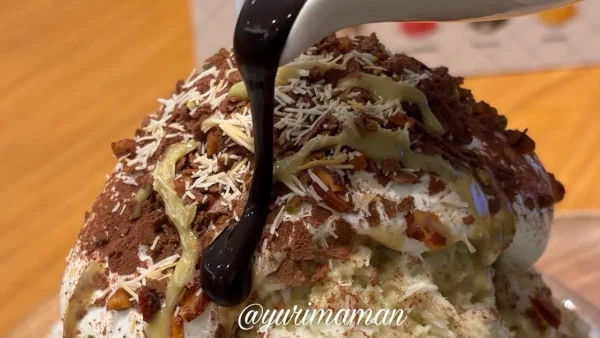 ココスのドバイチョコかき氷にチョコソースをかけるようす