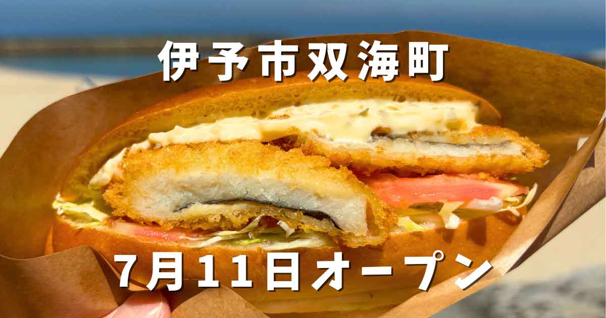 Close-up of a crispy fried cutlet sandwich with lettuce in a paper wrapper, held at the beach, overlaid with Japanese text announcing opening on July 11 in Iyo City Futami-cho.