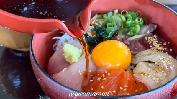 ひぶりめしに卵とタレをかけている様子