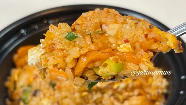 炭火焼豚とキムチが入ったキムチ炒飯をスプーンですくった様子