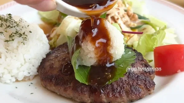 和風ハンバーグの大根おろしにソースをかける様子