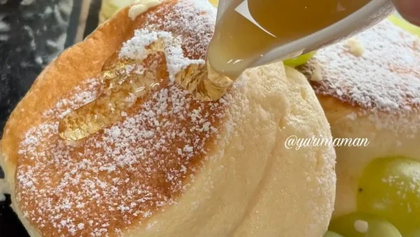 シャインマスカットのスフレパンケーキにはちみつをかける様子